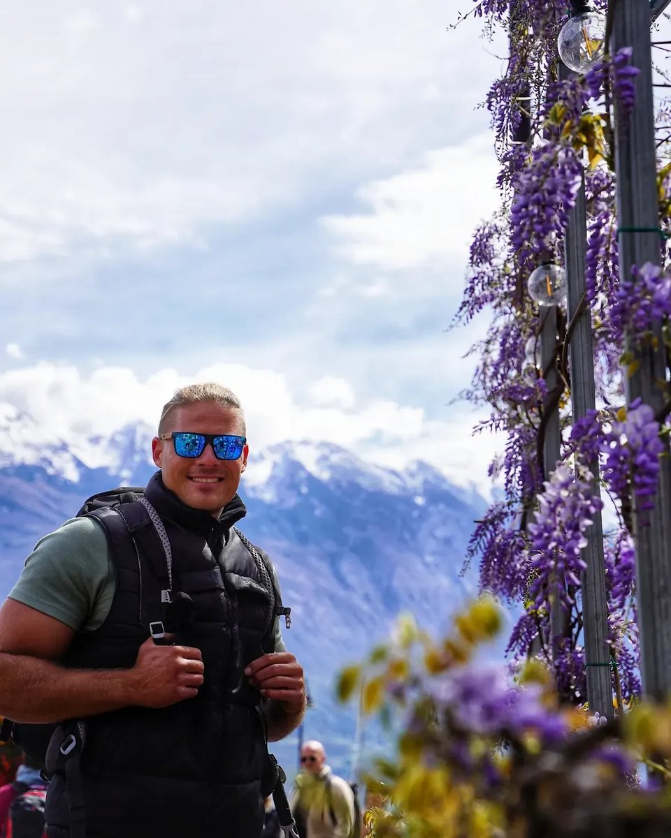 Cedric mit Wanderrucksack vor einer verschneiten Bergkulisse.