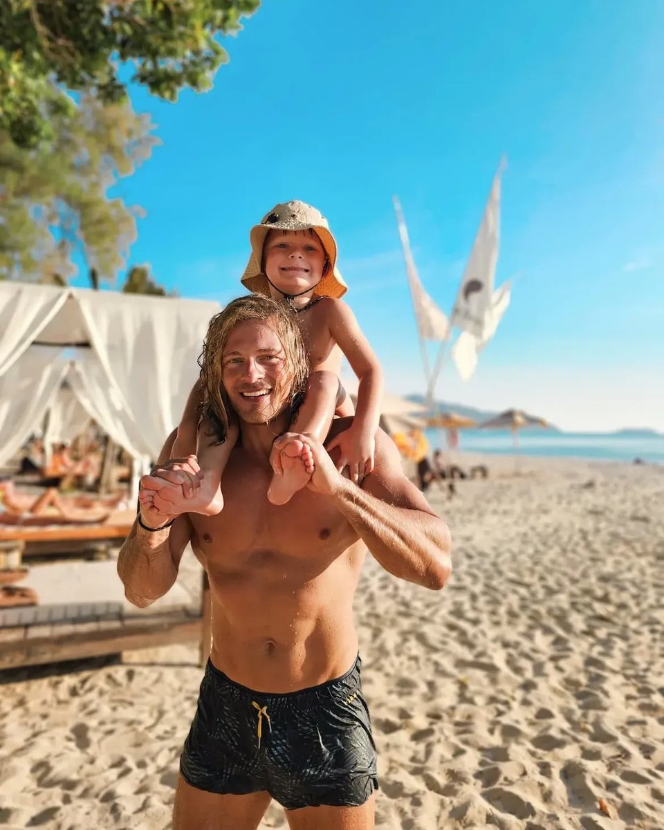 Cedric am Strand, ein Kind sitzt lachend auf seinen Schultern.